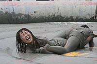 Photograph of two women wrestling and covered in mud