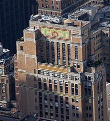 Aerial view of detailing on an upper-story setback, with mosaic tile and tan brick