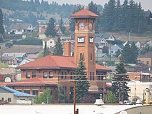 A former brick rail depot with a clock tower. Beneath are the letters KXLF in white mounted on blue.