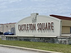 A sign reading "Castleton Square", in a patch of grass outside a shopping mall parking lot.