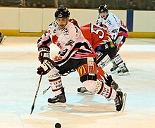 Photographie de Vincent Bachet qui patine le regard vers le palet sur la glace.