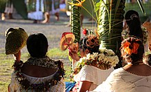 Photographie de femmes vues de dos, s'abritant du soleil avec des éventails.