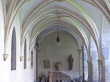 Photographie couleur montrant une aile de cloître, dans laquelle des objets archéologiques sont exposés.