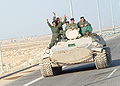 Iraqi military men riding tank along highway in Iraq