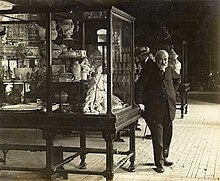 Photo d'un homme posant devant une vitrine.