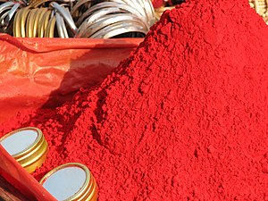 Vermilion is similar to scarlet, but slightly more orange. This is sindoor, a red cosmetic powder used in India; some Hindu women put a stripe of sindoor in their hair to show they are married.