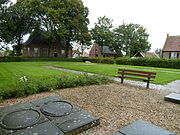 Gezicht op de bovenzijde van de wierde. In het gras de contouren van de vroegere kerk, links op de achtergrond de weem (pastorie) en uiterst rechts de kosterij.