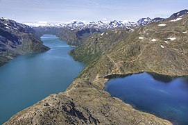 Grand lac allongé aux eaux turquoises vu depuis une arrête rocheuse près d'un petit lac.