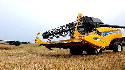 Gele maaidorser met een graanmaaibord dat voorzien is van verticale schaarmessen aan de zijkanten.