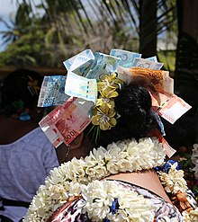 Photographie de la coiffure d'une danseuse, avec des billets de francs Pacifique épinglés dans les cheveux.