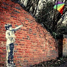 A mural by Hendog of a boy flying a rainbow-coloured kite.