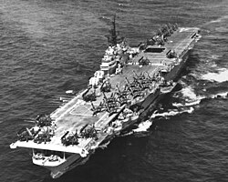 A large ship with a flight deck containing aircraft at sea