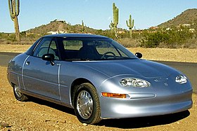 Three-quarters view picture of a silver electric vehicle, taken in what seems to be a desert.