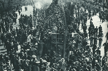 Photographie en noir et blanc d'une foule massée autour d'une route.