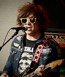 A man with yellow sunglasses singing and playing guitar