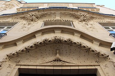 Peacocks and motifs inspired by their feathers (and sometimes other animals) – Relief above the door of Rue Octave-Feuillet no. 19 in Paris, by Maurice Du Bois d’Auberville (1910)