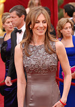 A picture of a brunette. She wears a bluish grey dress and she smiles.