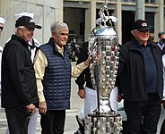 Rick Mears, Al Unser, and A. J. Foyt standing beside the Borg-Warner Trophy in 2021