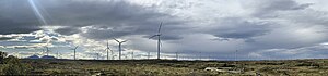 Vindkraftverket består av i alt 68 vindmøller (vindturbiner) som er plassert i lyng- og myrlandskapet nordøst på øya. Bak sees Tustnastabban (Tustnafjella). Foto: Fortegnet panorama 2024