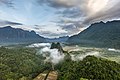 Pitons karstiques, brume et nuages colorés au lever du soleil, vus du sommet du mont Nam Xay (côté nord), pendant la mousson, à Vang Vieng. Juin 2020.