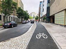 An asphalt bike lane on Lower Water Street in downtown Halifax. The general traffic lanes and car parking spaces are to the left of the bike lane. The bike lane itself is at the same level as the sidewalk, on the right.