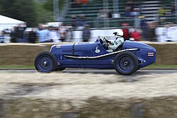 Bira 1936 Maserati 8CM, vista orixinal coa librea azul coa bandeira de Siam na cola e o emblema de Whitemouse xusto por diante da abertura do habitáculo.