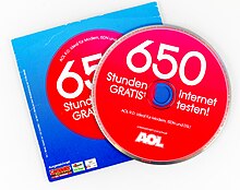 Eine CD-ROM in roter Farbe liegt schräg über der zugehörigen Papierhülle in rot-blauer Farbe.