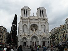 Vue en contre-plongée de nuit d'une façade savamment éclairée de type baroque possédant fronton, décorations et statues.