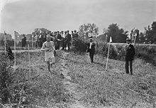 Photographie en noir et blanc d'un athlète qui court sur la pelouse.