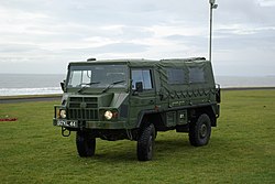 four wheeled vehicle on green field, it has a canvas canopy over the rear and at the extreme rear a radio mast has been extended