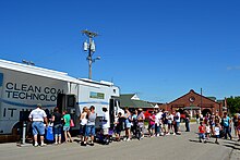 Photo of a crowd lining up outside a truck. The truck has "Clean coal technology. It works." painted on the side.