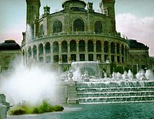 Photographie colorisée amateur d'une vue en biais du palais du Trocadéro depuis sa fontaine.