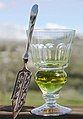 Image 24A reservoir glass filled with a naturally colored verte absinthe, next to an absinthe spoon (from List of alcoholic drinks)