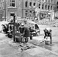 German women doing their washing at a water hydrant in a Berlin street, a knocked out German scout car stands beside them, 3 July 1945