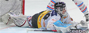 Photographie couleur d’un gardien de hockey sur glace, couché sur la glace