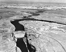 Aerial view of Glen Canyon Dam and a partially filled Lake Powell behind it.