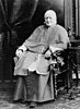 A seated man with tonsure in Roman Catholic priest's vestments