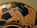 Escena de pancración: o pancracionista da dereita trata de arrancarlle o ollo ó seu opoñente; o árbitro está a piques de golpealo por esta falta. Detalle dun kylix ático de figuras vermellas no Museo Británico, 490-480 a.C. De Vulci, Italia.