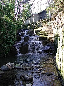 Photo d'une cascade avec en arrière-plan une bâtisse.