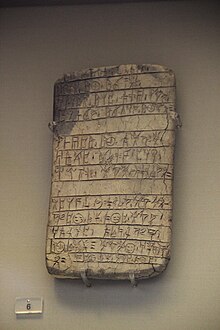 A clay tablet, approximately twice as tall as it is wide, inscribed with Linear B signs