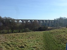 stone viaduct with múltiple arches, partly obscured by tress