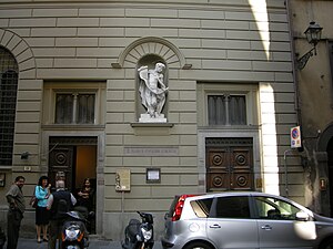 A grey-white building with a white marble statue in a niche at first floor level