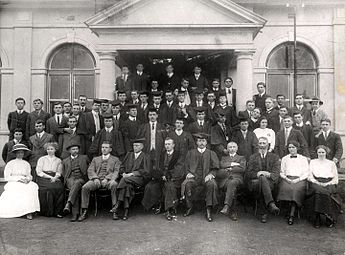 Studente en personeel van die Voorbereidende en Teologiese Skool op Potchefstroom voor die eerste gebou, 1913. Voor: Hester Coetzee, Betsie Postma, S.G Yssel, J.J.A. Coetzee, prof. Ferdinand Postma, prof. J.D. du Toit (Totius), prof. A.P.C. Duvenage, prof. Jan Kamp, Piet van der Walt, Rachel Wentzel, Vera Gill. Tweede ry: Nollie Vermaas, G.P. van der Linde, J.V. Coetzee, D.G. Venter, C.J.H. de Wet, J.C. van der Walt, D.N. Kotzé, H.F. Duvenage, Vera Pienaar, Frikkie Potgieter, J.L.M. Wiechers. Derde ry: Piet Coetzee, Jan Triechaardt, Nic Steyn, B.J. de Klerk, J.H. Boneschans, H.S. van Jaarsveld, Pieter Coetzee. Vierde ry: Prof. Joon van Rooy, ene Oosthuizen, C.W.M. Du Toit, E.L.J. Venter, T.D. Venter, Daan Marais, J.V. Coetzee, Lou van Rooy, A.S.E. Yssel, H. van der Walt, S.P. Engelbrecht, Izak le Roux, ene Marais, L.J. du Plessis. Vyfde ry: ene Scholtemeyer, Willie Geere.