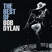 A black-and-white profile of Dylan sitting onstage playing a guitar