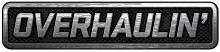 A simple logo spelling the word "Overhaulin'" in block capital letters in silver over what appears to be a car grill or interlaced gray mesh