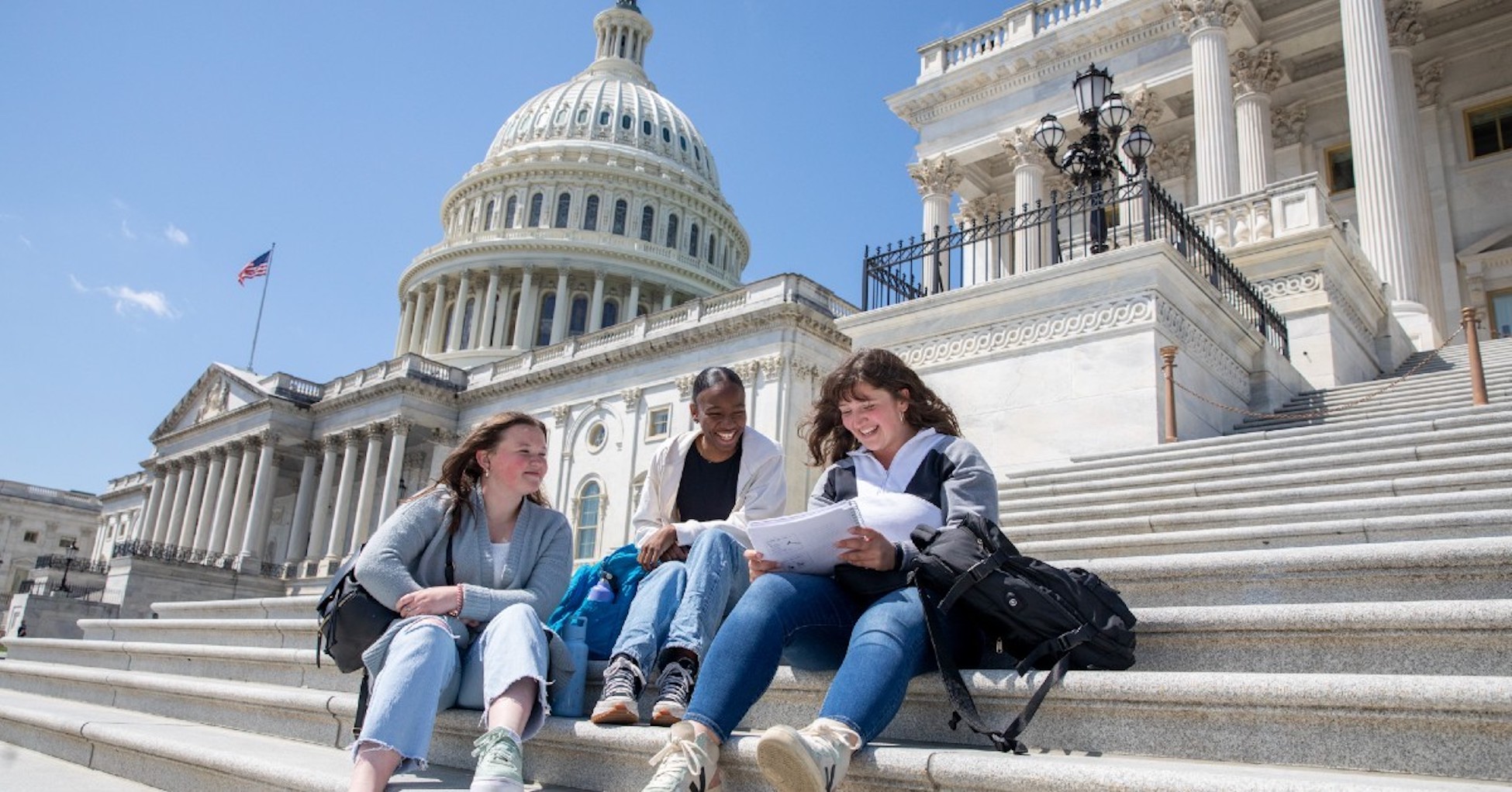 girls sitting on the steps of the U.S. capitol doing school work