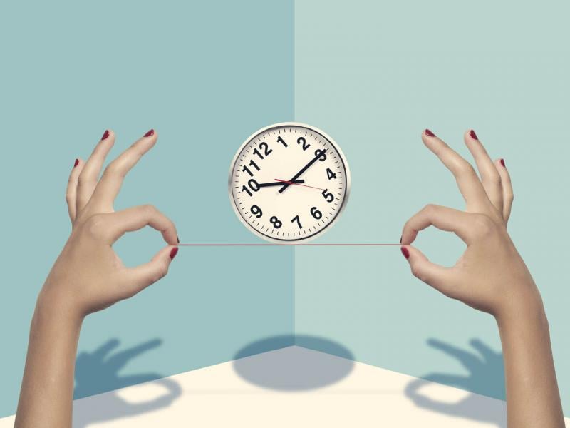 Two hands balancing a clock