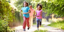 two kids running in front of an adult