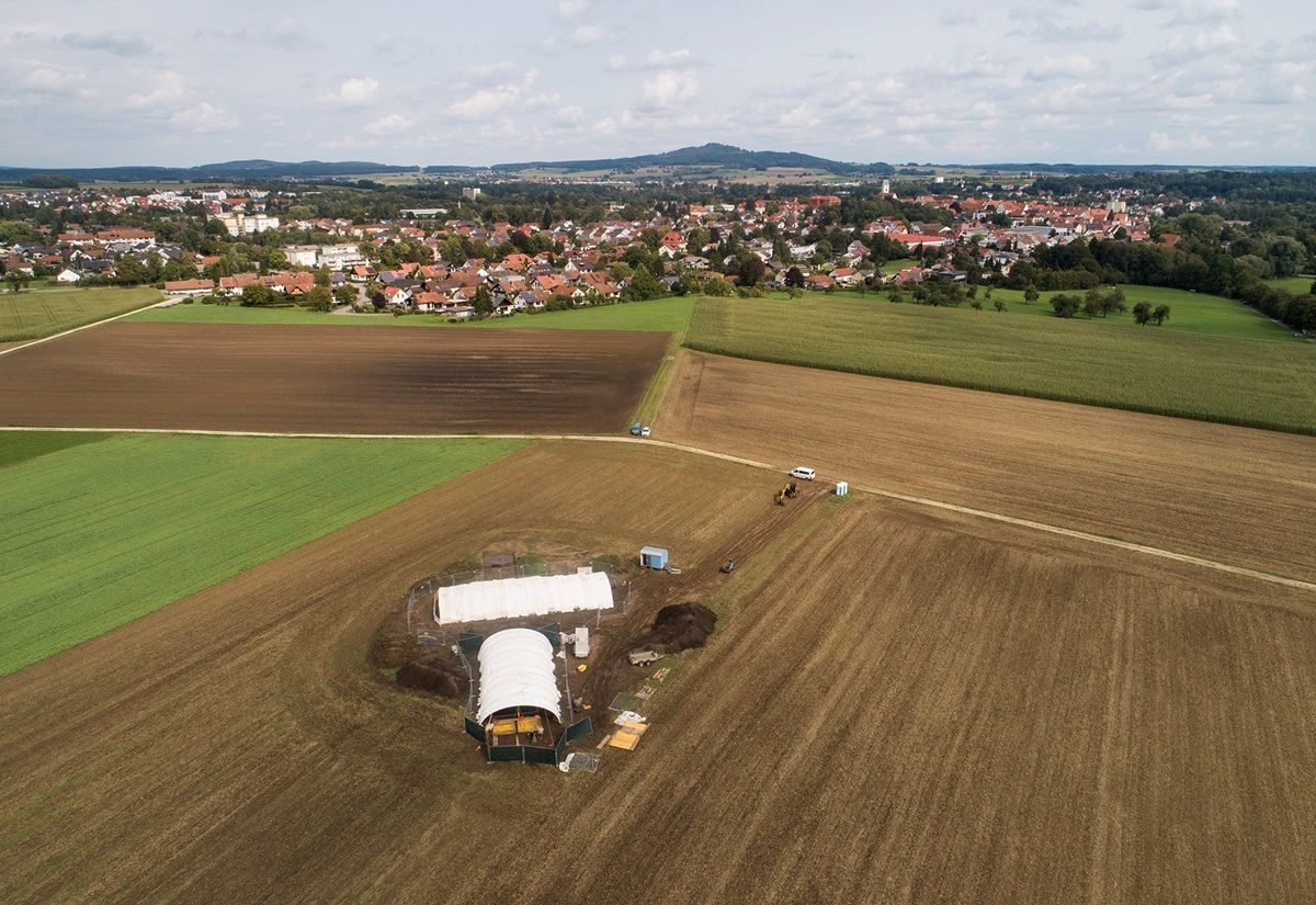 Drohnenaufnahme mit der Grabungsstätte im Vordergrund, Riedlingen im Mittelgrund und dem Bussen im Hintergrund