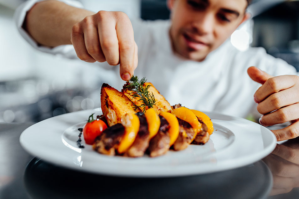 A culinary student garnishes a dish